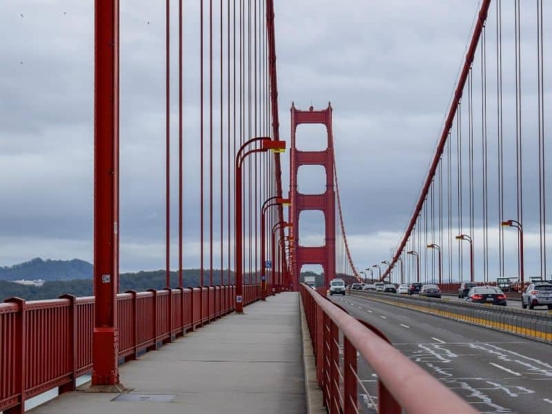 Pedestrian walking path on the Golden Gate Bridge, a red suspension bridge, on a foggy San Francisco date.