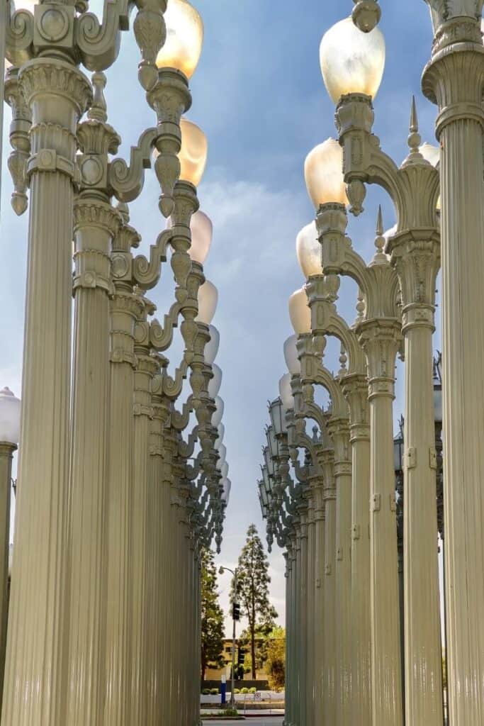 Tall white vintage lampposts standing in rows as part of an urban art installation at LACMA