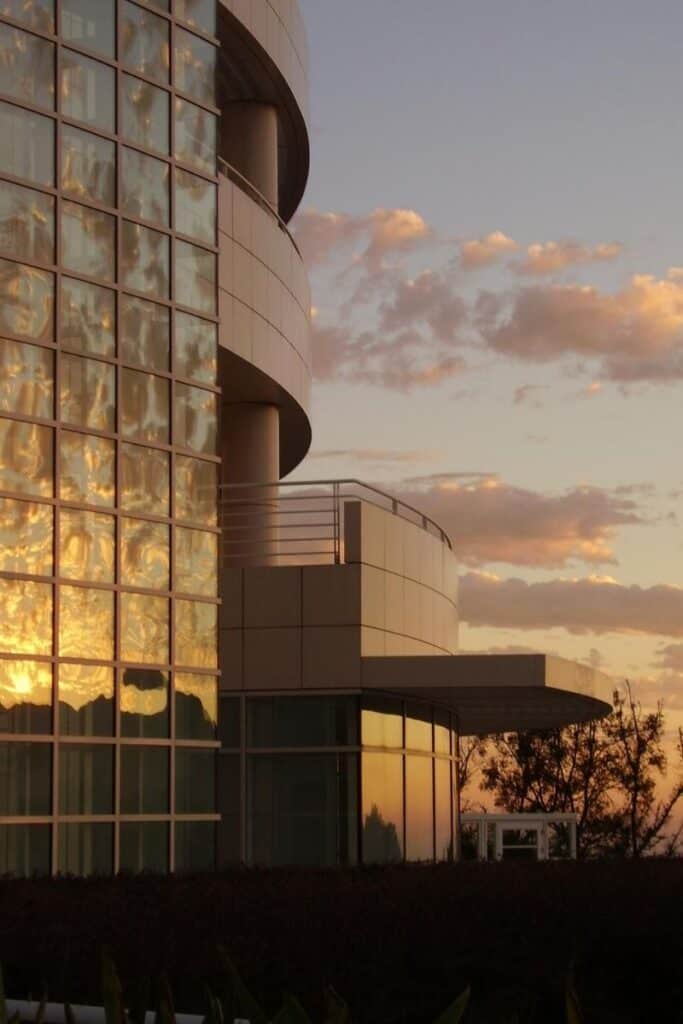 Reflective glass panels of an LA building showing the colors of the sunset and clouds.