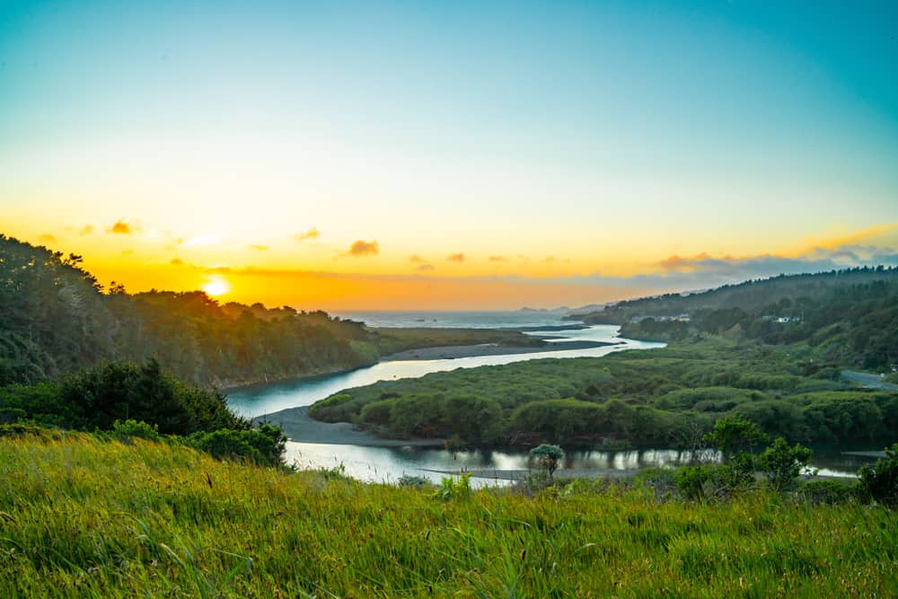 View from mountain of twists of Gualala river emptying into the Pacific Ocean with sunset tones of blue and orange