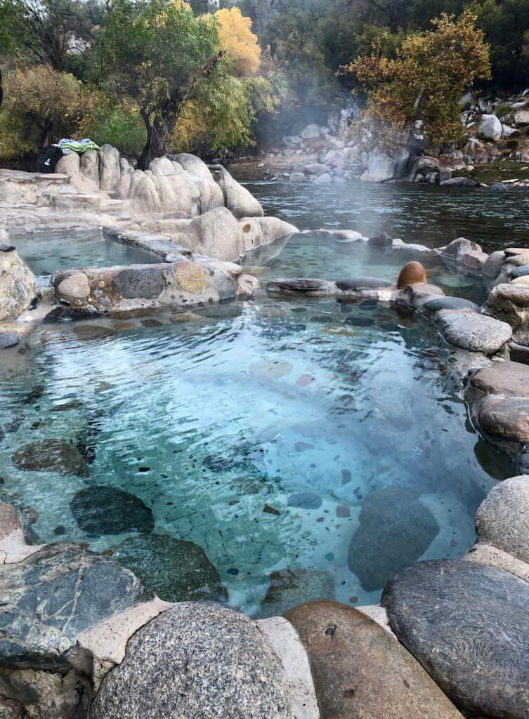 vertical photo of little hot spring pools next to the river