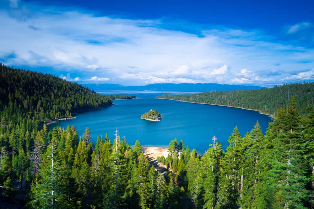 The view of Emerald Bay from above - lots of pine trees surrounding a turquoise blue lake with a small island in the center.