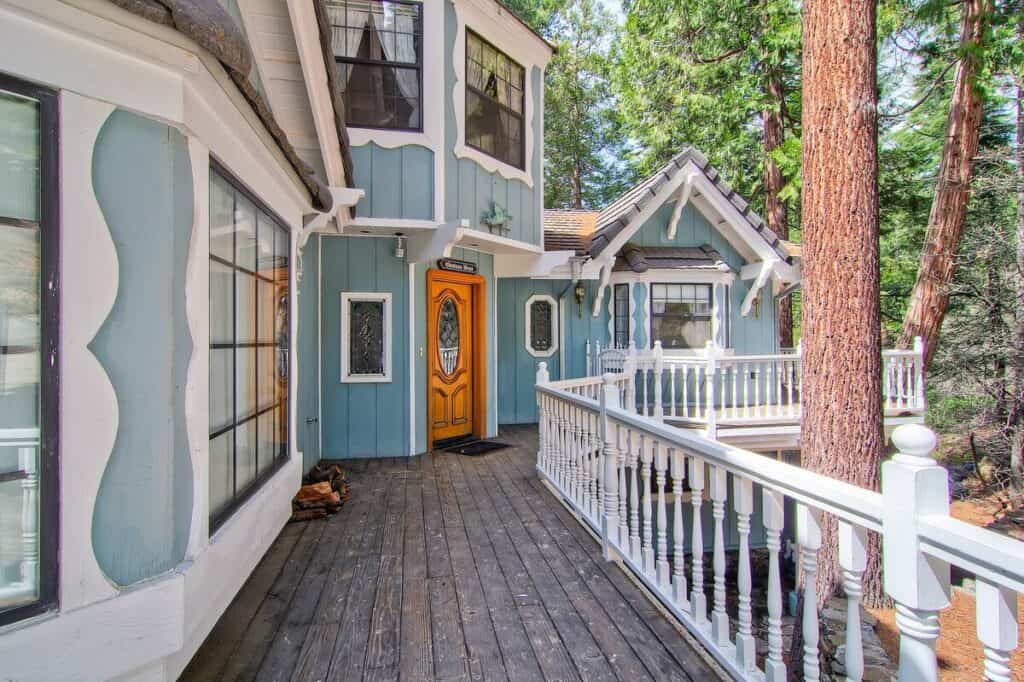 Victorian-looking baby blue house with white detailing in forest