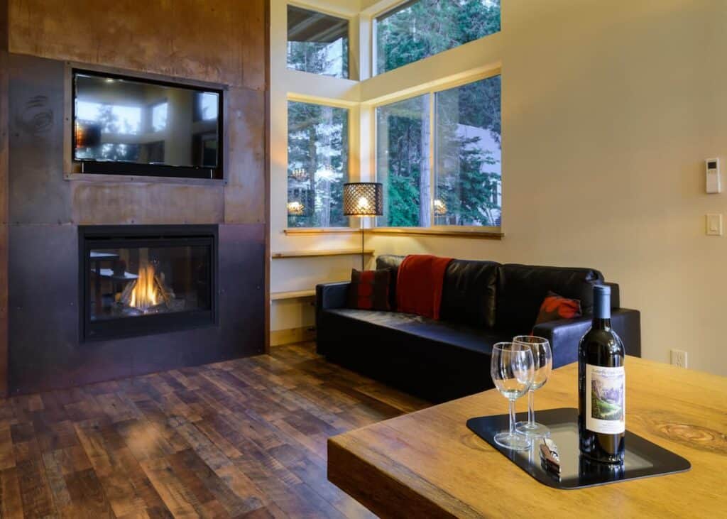 Bottle of wine with two glasses with leather sofa and fireplace