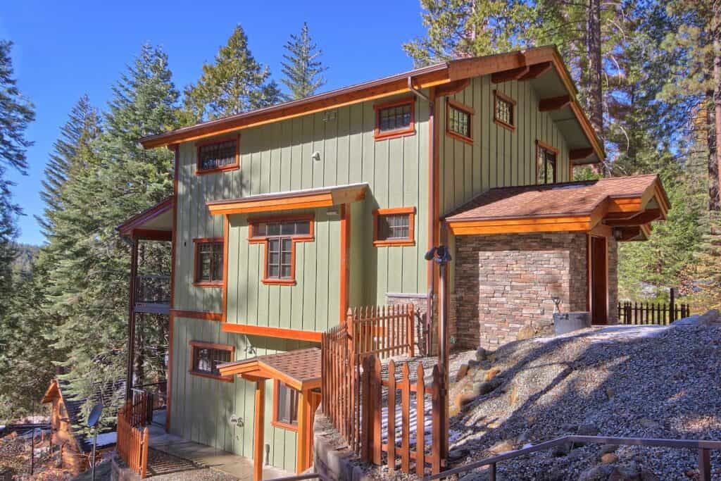 Green multi-story cabin with pine trees