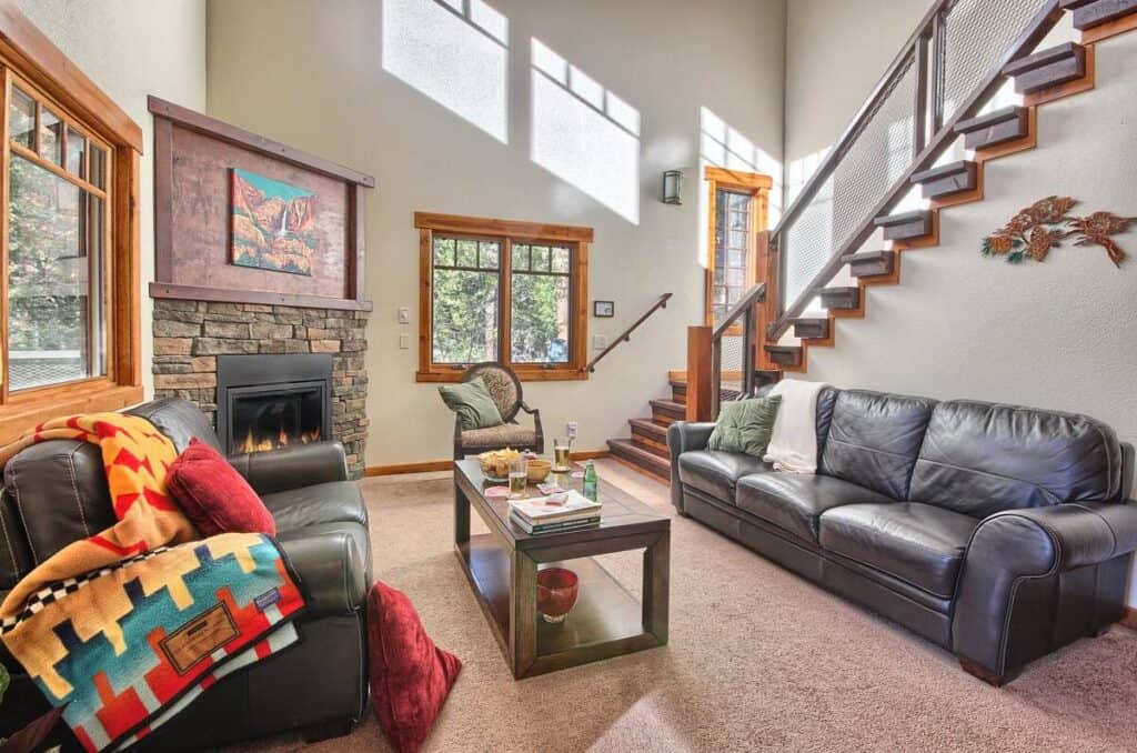 Living room with staircase with two sofas and a roaring fireplace and blankets