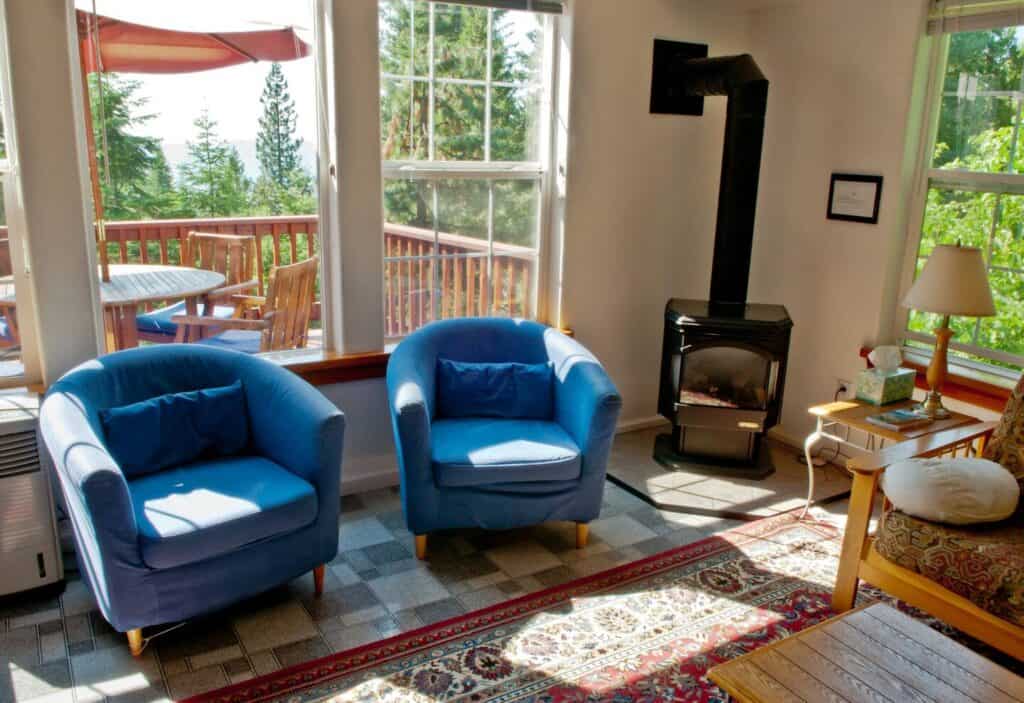 Two blue chairs plus wood fireplace and views of deck and landscape