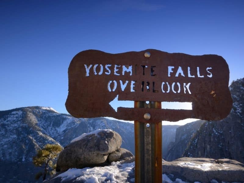 Sign that reads "Yosemite Falls Overlook" with snow in background showing it is winter in Yosemite.