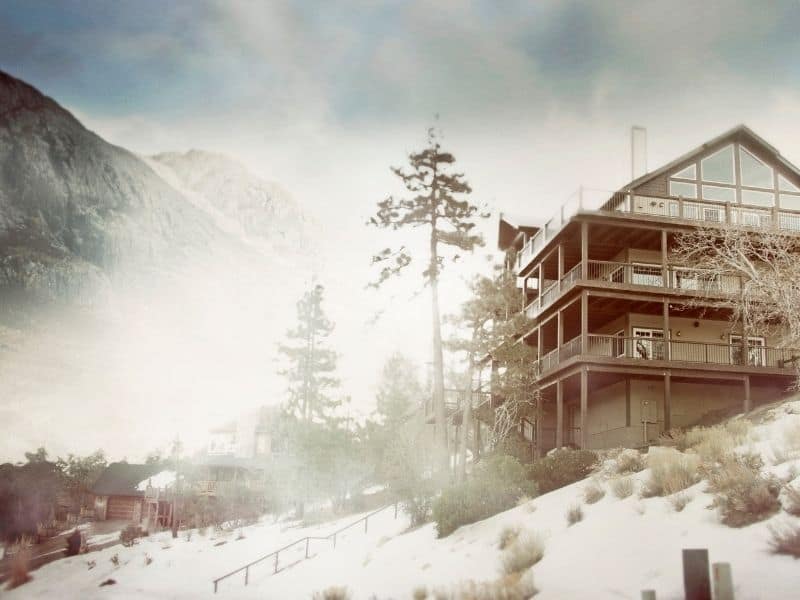 Misty view of large cabin-looking hotel on a snowy day