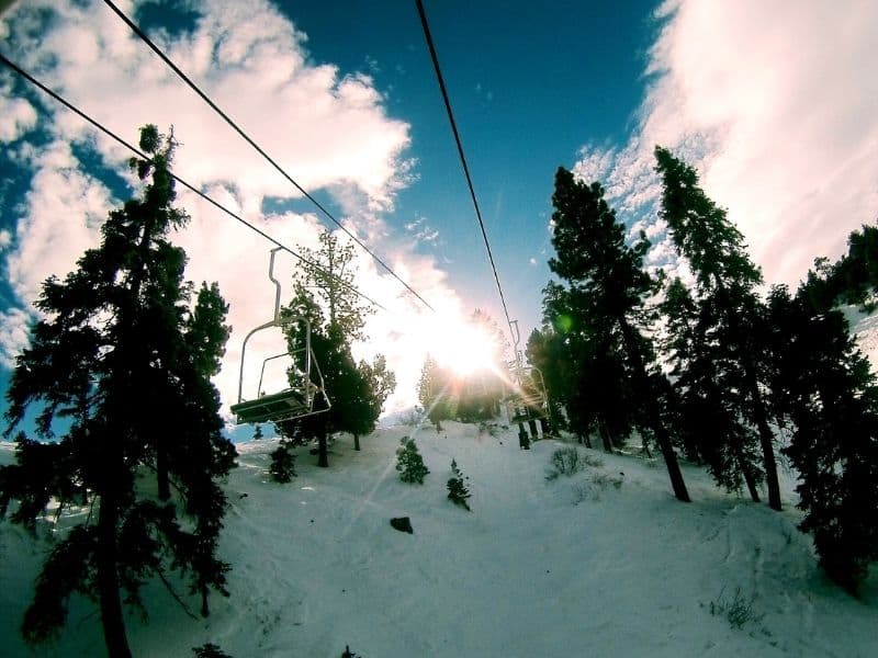 Sunburst on a partly cloudy day of Big Bear in winter chair lifts for skiing and snowboarding 