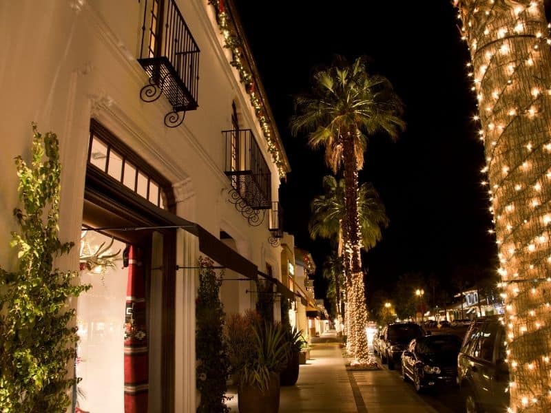 A main street in Palm Springs California with Christmas lights strung up on palm trees