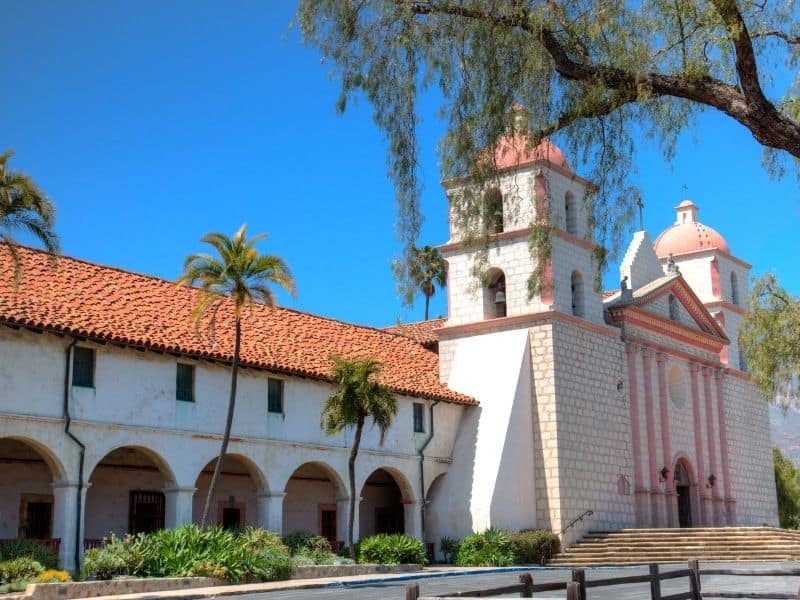 The historic Santa Barbara Mission done in the Franciscan architecture style: a Spanish-looking white and red-bricked church.