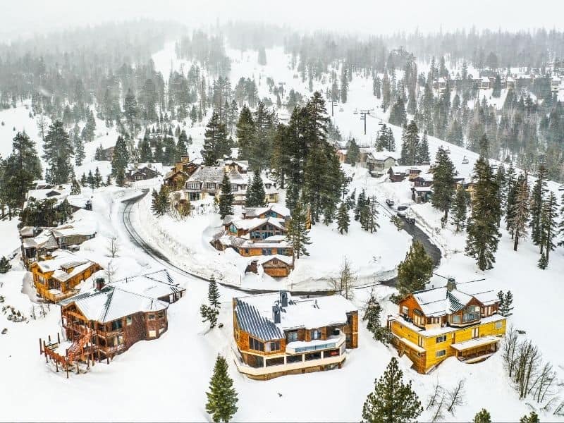 Aerial view of Mammoth Lakes in winter with lots of cabins and hotels covered in snow.