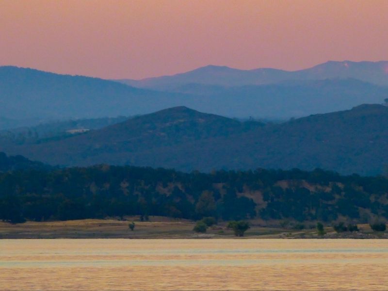 Grassy plain in foreground with mountains in background and pink sky at sunset.