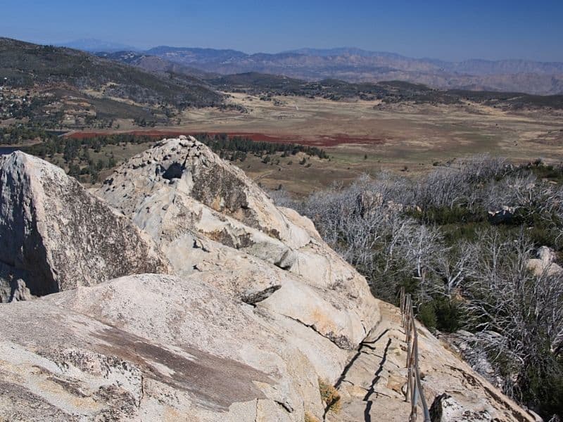 Large rock in foreground with view from higher elevation of the plains and trees below.