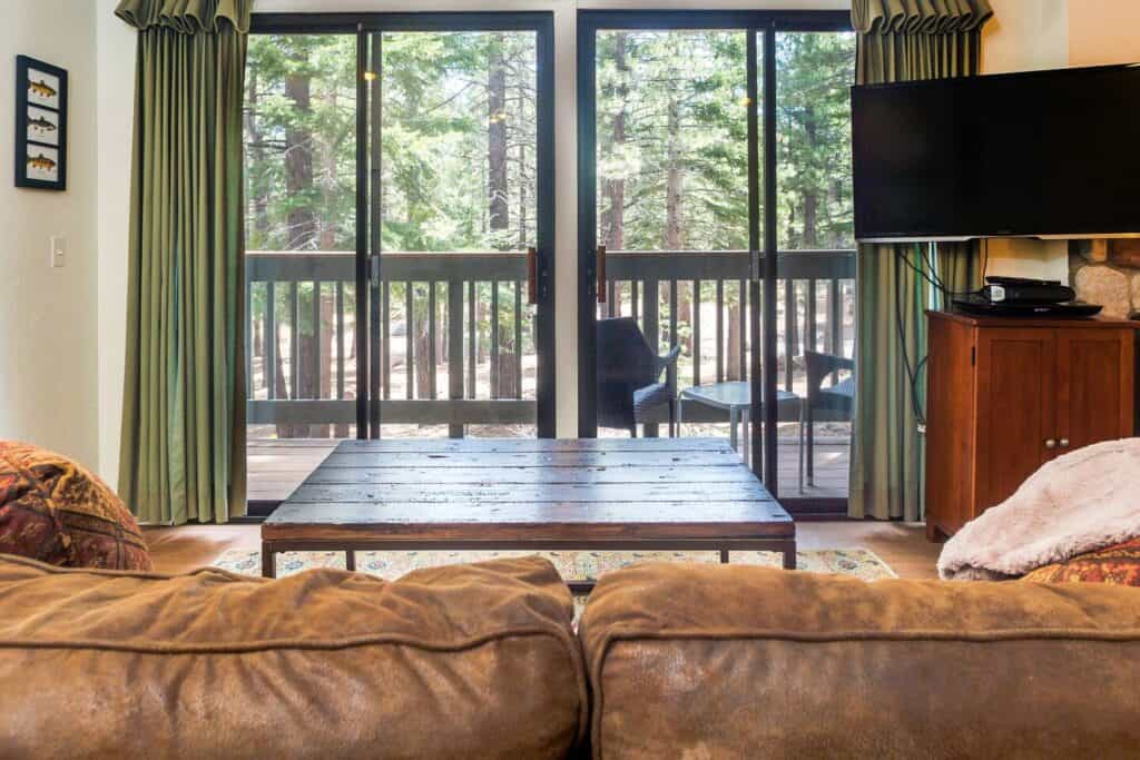 A cozy sofa looking out onto a scene of pine trees in a modern looking apartment.