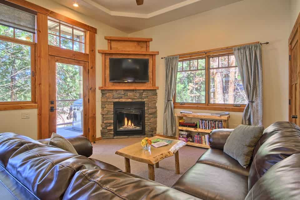 Soft leather sofa with coffee table and lit fireplace with lots of windows