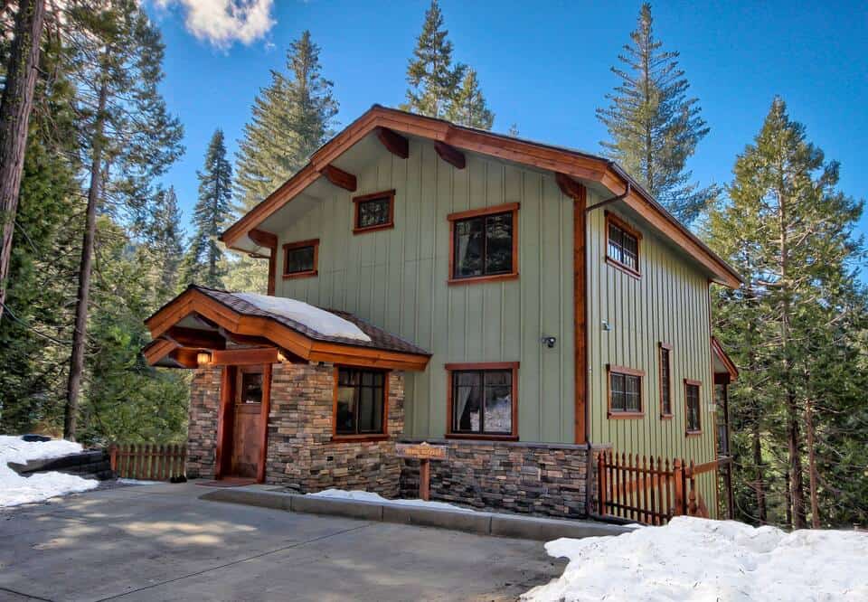 Standalone green cabin with snow on a sunny day