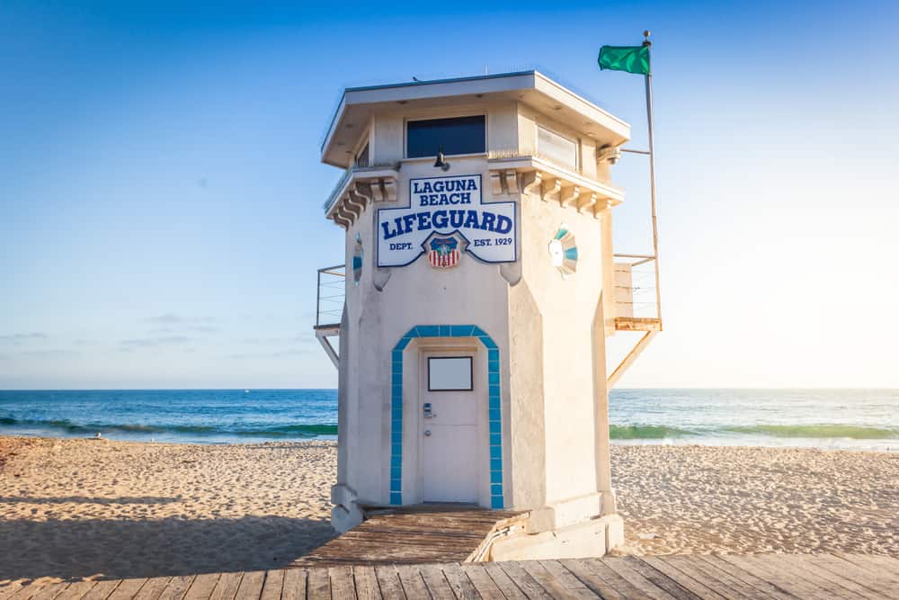 Laguna Beach lifeguard tower on an empty beach with a small flag, on a beach with blue water behind it