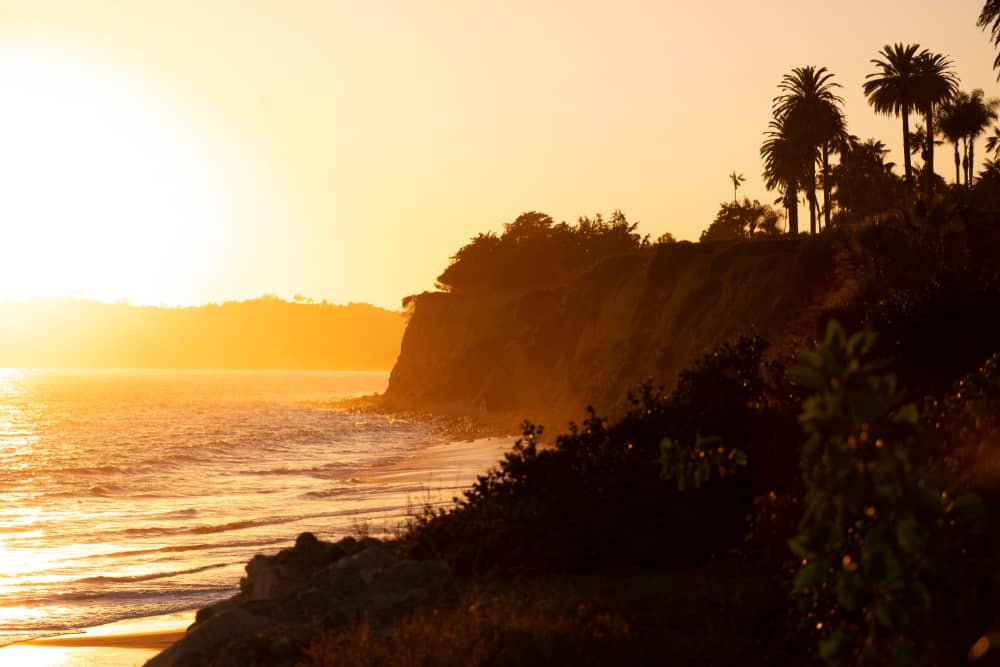 A beautiful orange and pink sunset on the cliffs of Butterfly Beach, the perfect end to a weekend in Santa Barbara itinerary.