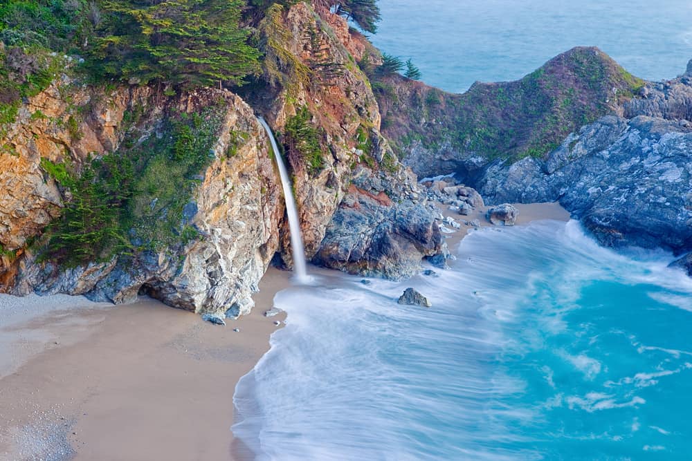 Waterfall emptying out into the beach along the sea in Big Sur