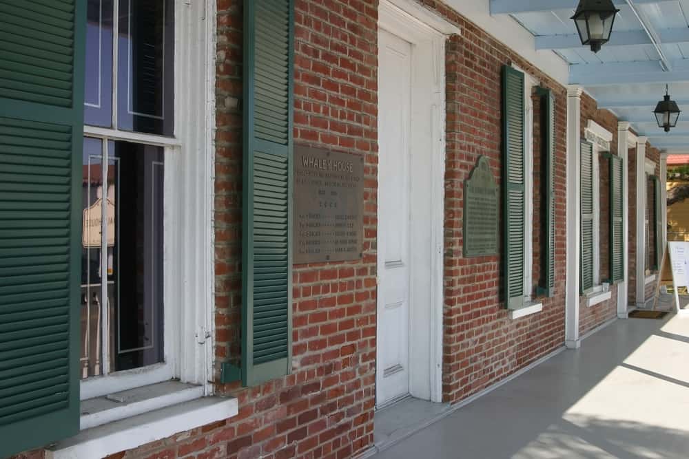 Historic red brick building with green shutters - part of Whaley House Museum, a haunted house in San Diego. Weekend itinerary must-see!