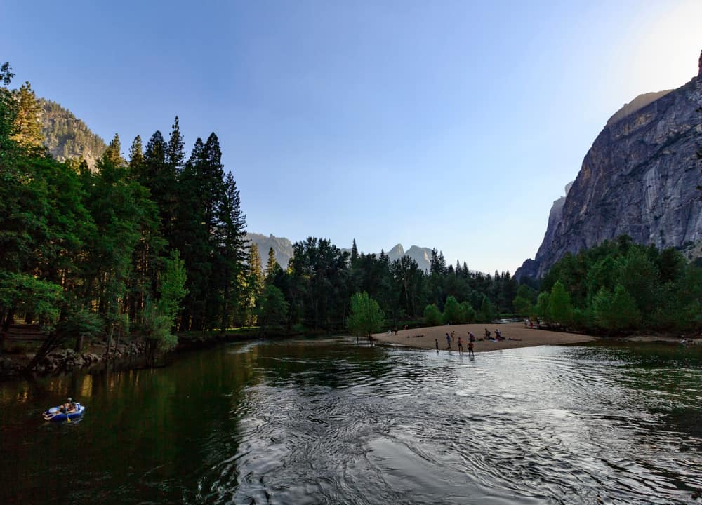 People rafting in calm water in Merced River of Yosemite in late afternoon light.