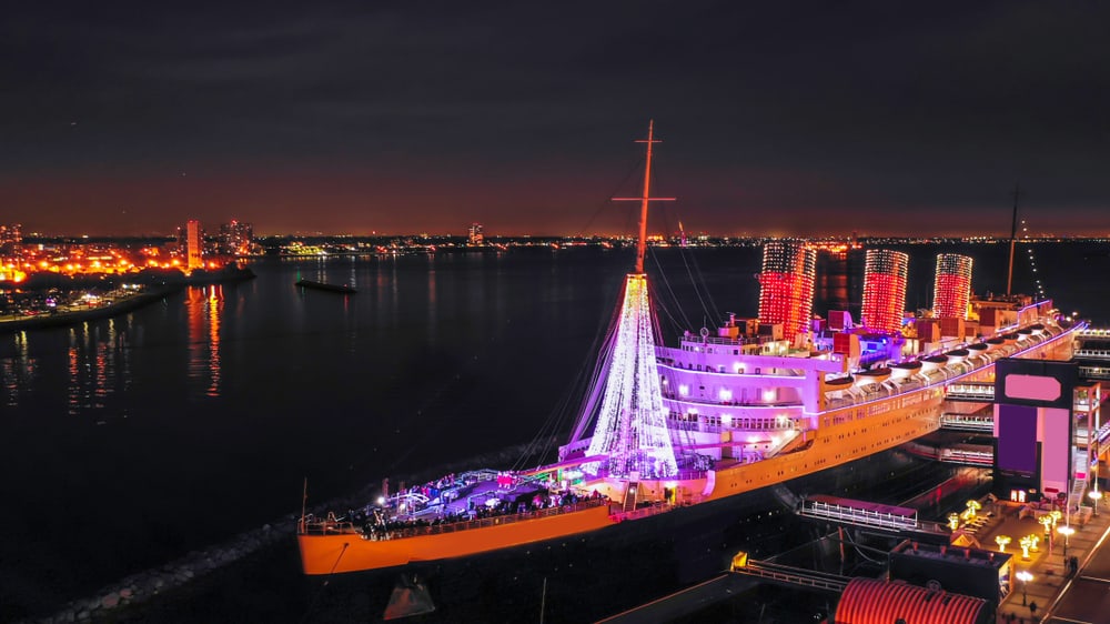 A lit-up boat with red and pink lights, the RMS Queen Mary in Long Beach California: a California Christmas hot spot