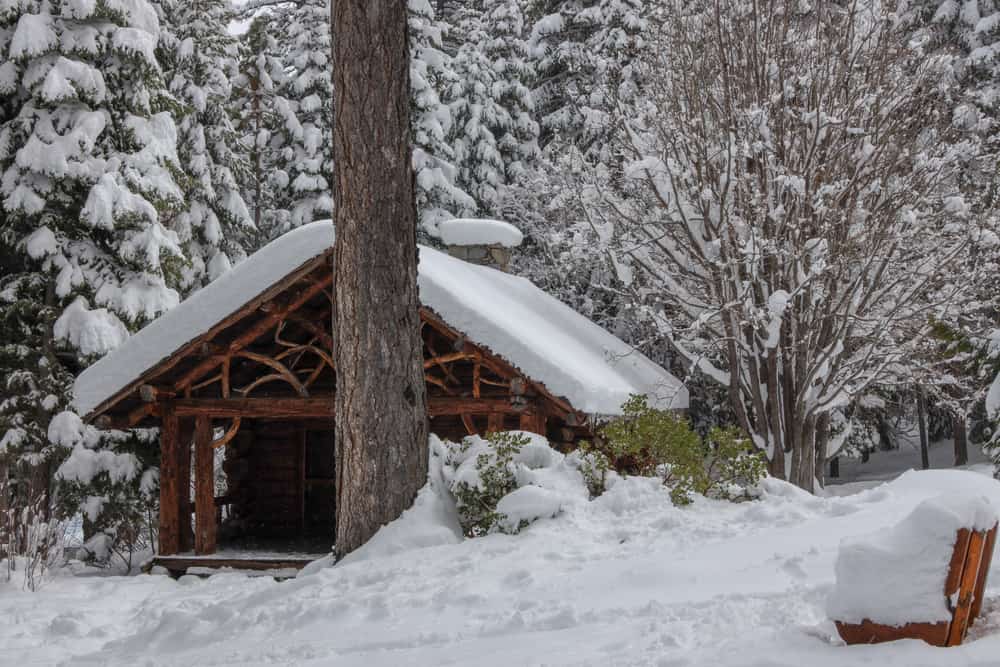 A historic wooden structure at Tallac Historic Site covered in snow with path from hikers.