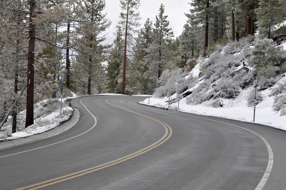 A snow-plowed winding road which leads to Lake Tahoe with snow on the sides of the road