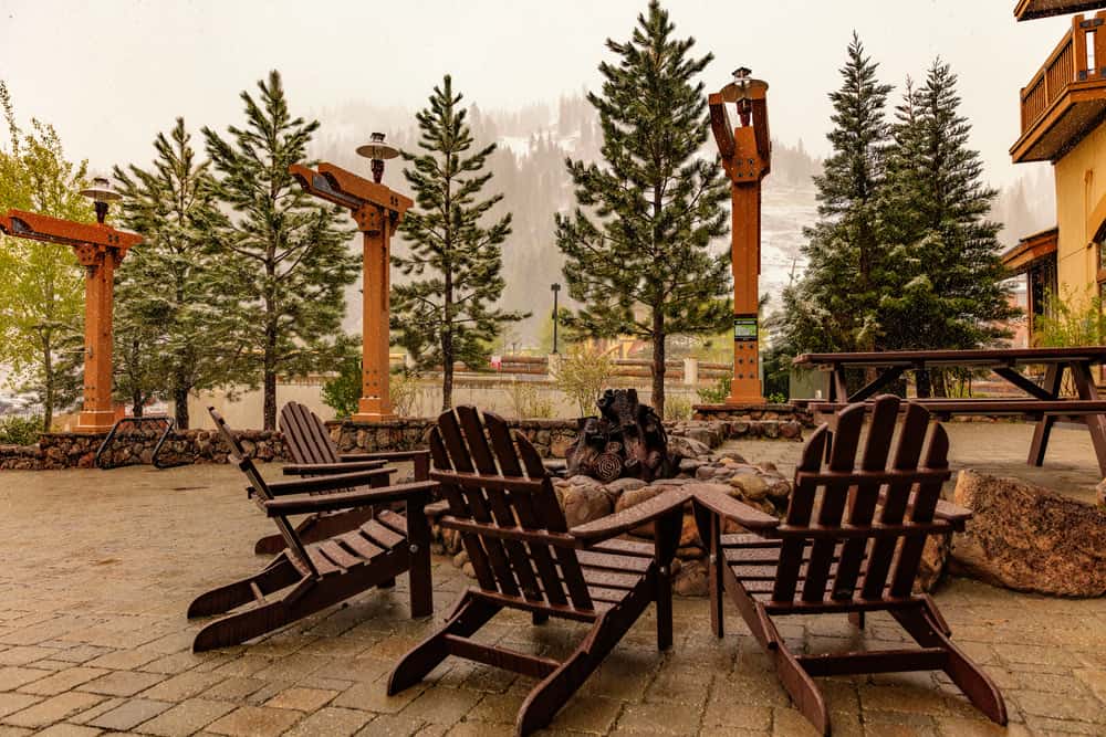 Adirondack wooden chairs assembled around a fire pit in Olympic Village on a dreary day with some snow in the forecast.