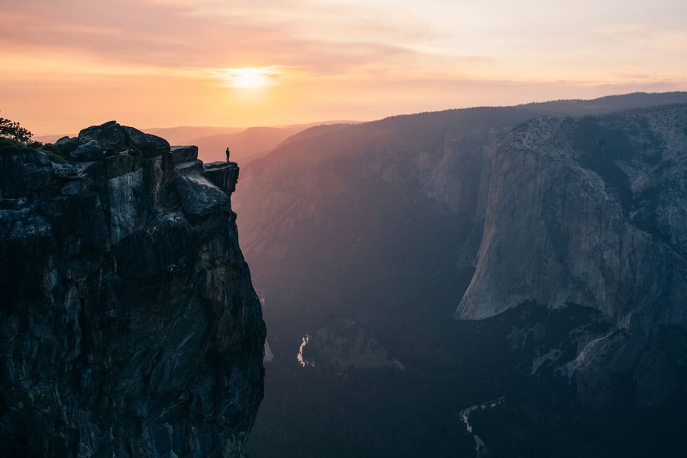 Man at Taft point at sunset standing on cliff edge