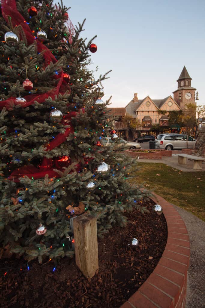 Close up of Christmas tree with European-looking village behind it in Solvang California at Christmas time