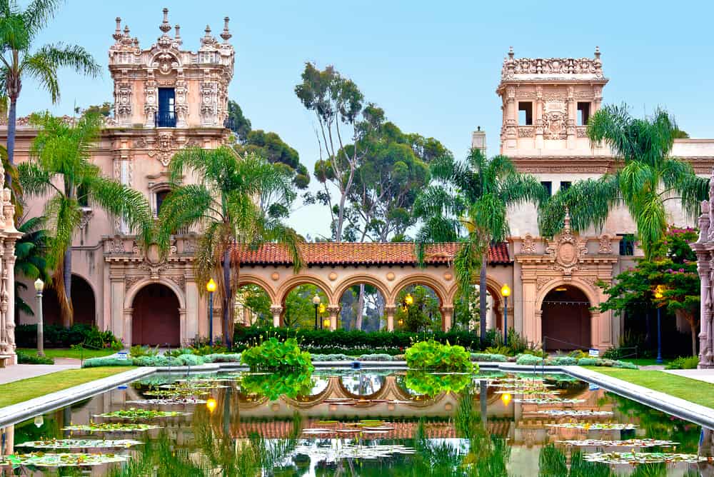 Balboa Park castle-looking structure with pond in front and green trees with blue sky.