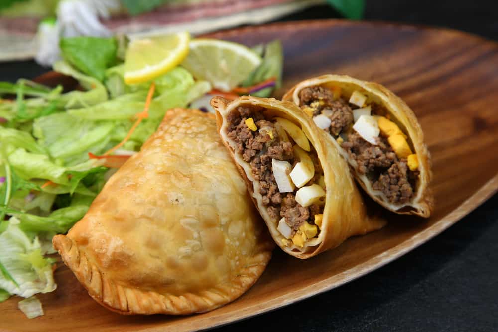 Empanadas (wheat pastries stuffed with filling) with beef and hard boiled egg served with salad.