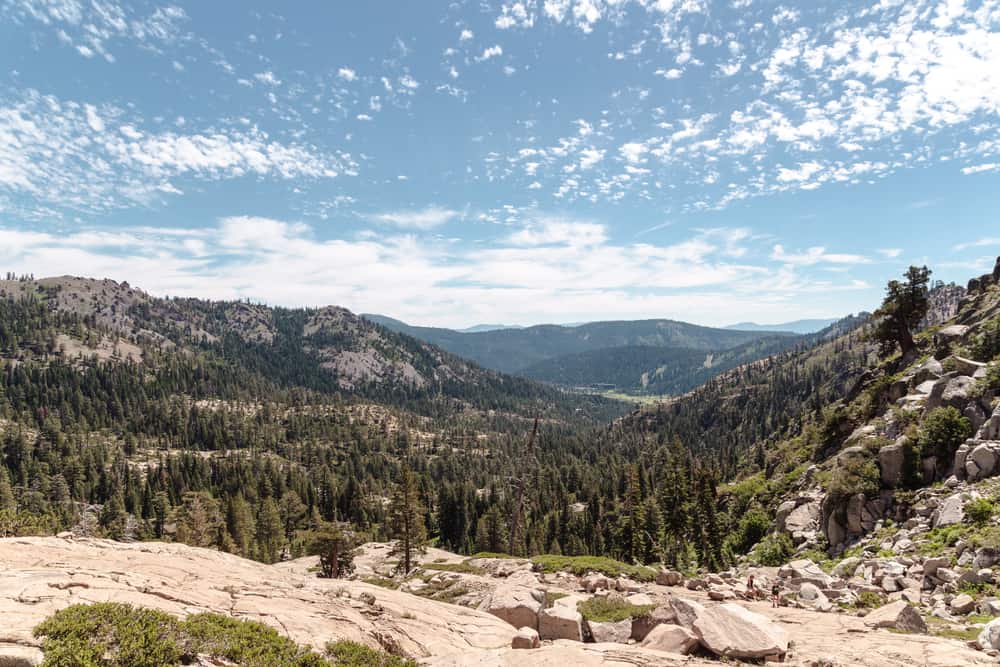 Hiking from High Camp to Shirley Lake with a beautiful view on the hike of the pine trees, mountains, and blue sky dotted with small clouds.