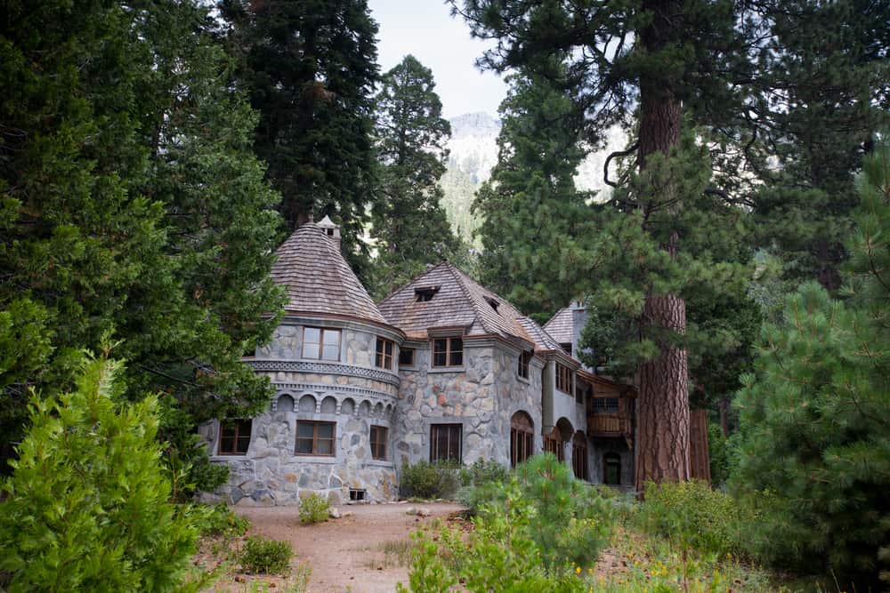 Castle made of stone with a Scandinavian inspired design in the middle of a pine forest.