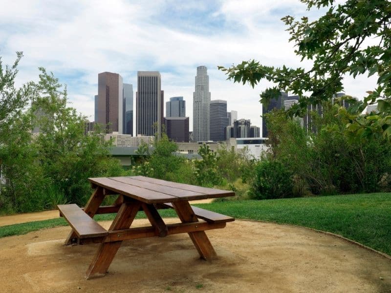 Empty picnic table in Los Angeles city park with a view of the LA skyline in the background on a partly cloudy day.