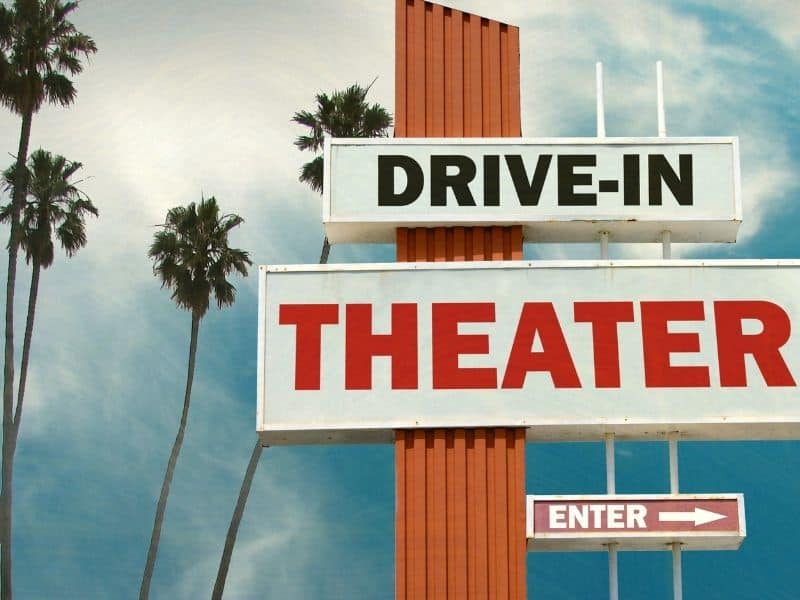 Cloudy sky with palm trees and text that reads "Drive in Theater" and "Enter" with an arrow pointing right.