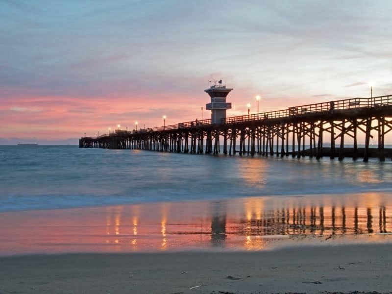 View of the water and the wooden pier at sunset, with the tide flowing out
