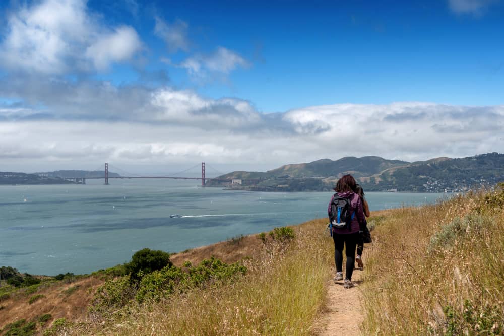 Hikers climbing Mt. Livermore in Angel Island State Park, with views of the Golden Gate Bridge