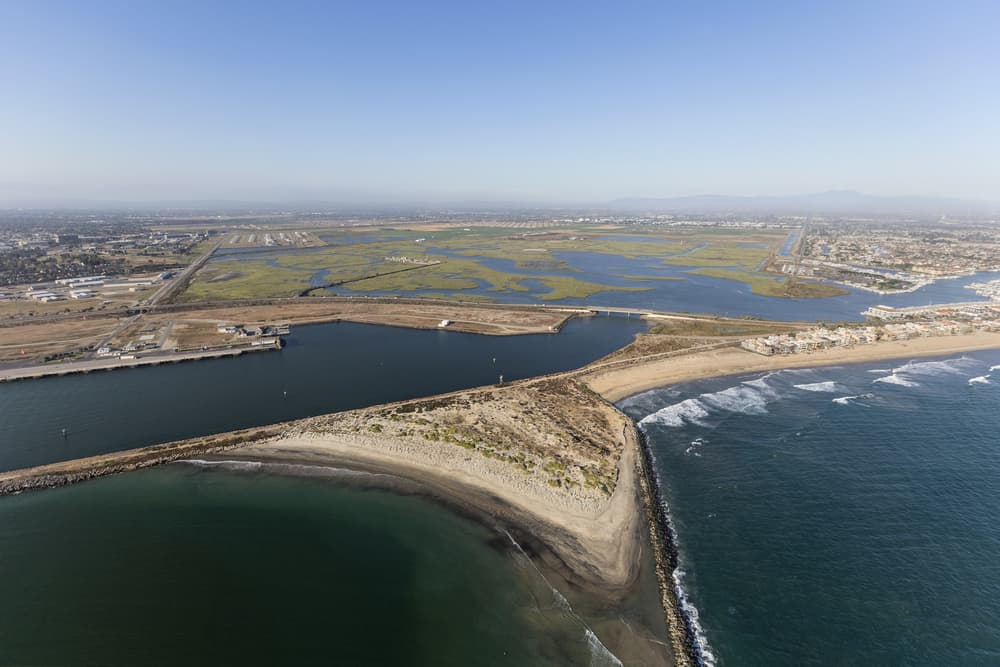 Aerial drone photo of sand meeting the ocean as well as salt marsh (green small islands in a bay) on a sunny day