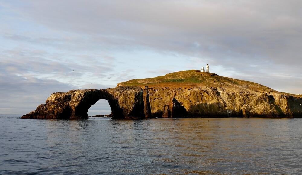 View of Anacapa Island, with its rock arch and lighthouse, as seen from a fishing boat.