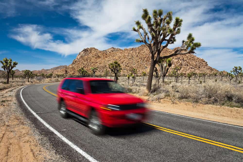 a red car driving through the joshua tree landscape