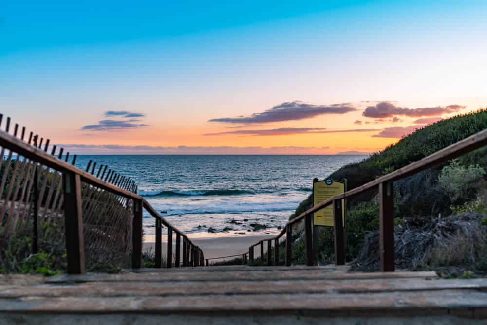 Sunset at a staircase in Crystal Cove State Park leading to the ocean