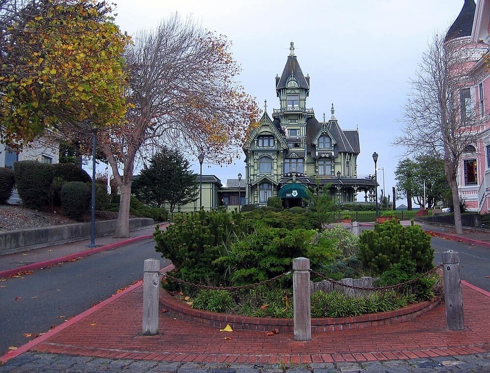 Small square filled with plant life in front of the famous green Victorian Carson Mansion multi-story house in Eureka, california