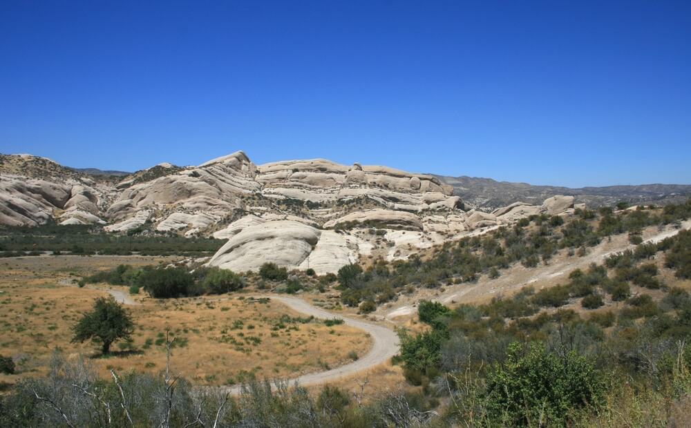 Mormon rocks in Phelan, California:  geological formations and a meadow beneath a blue sky on the road trip from Los Angeles to Vegas