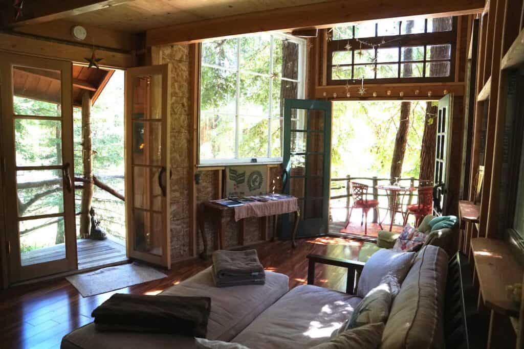 The living room of a South Bay Area California treehouse rental, with wooden details and comfortable, unpretentious furniture.