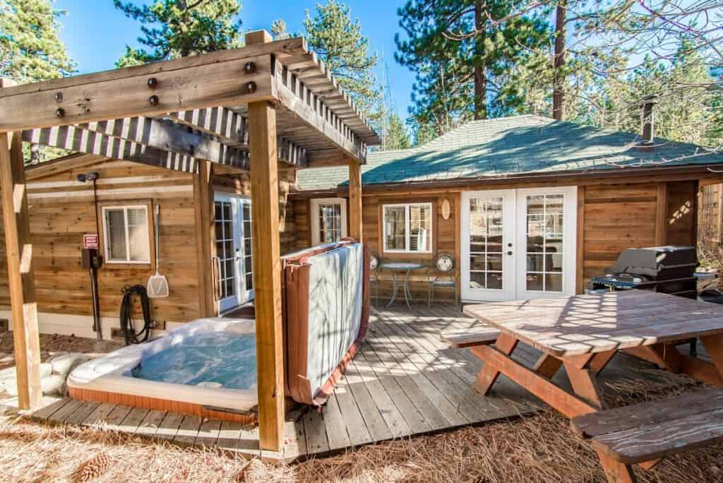 A wooden Tahoe Airbnb with a picnic table, grill, and hot tub available for use in the backyard.