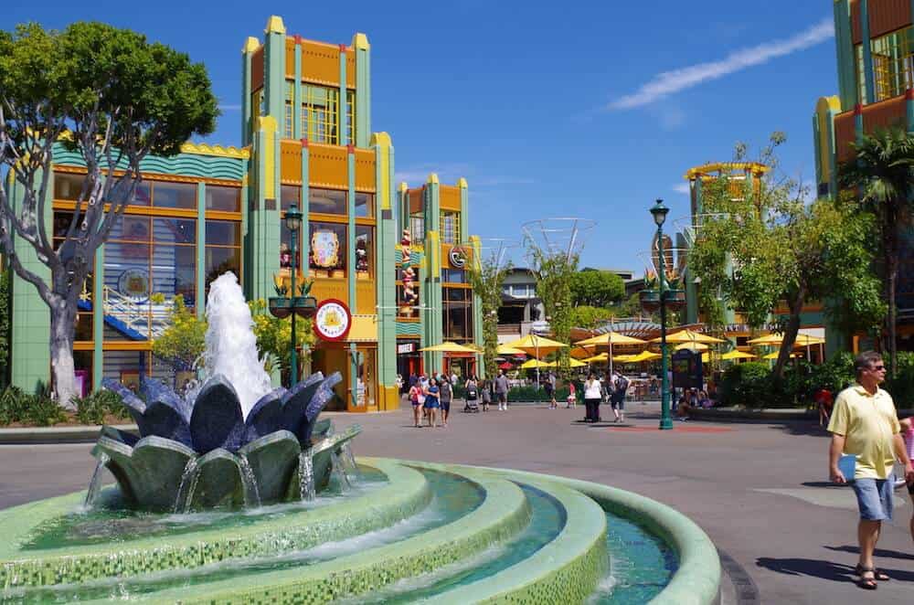 People walking around Downtown Disney with a water fountain and buildings in the daytime.